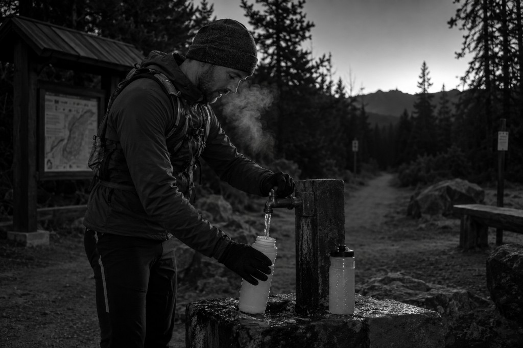 Athlete refilling bottles at a pre-dawn trailhead